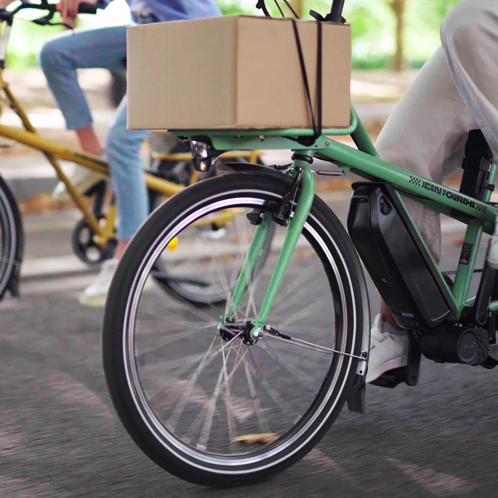 Un carton posé sur le rack avant d'un vélo vert