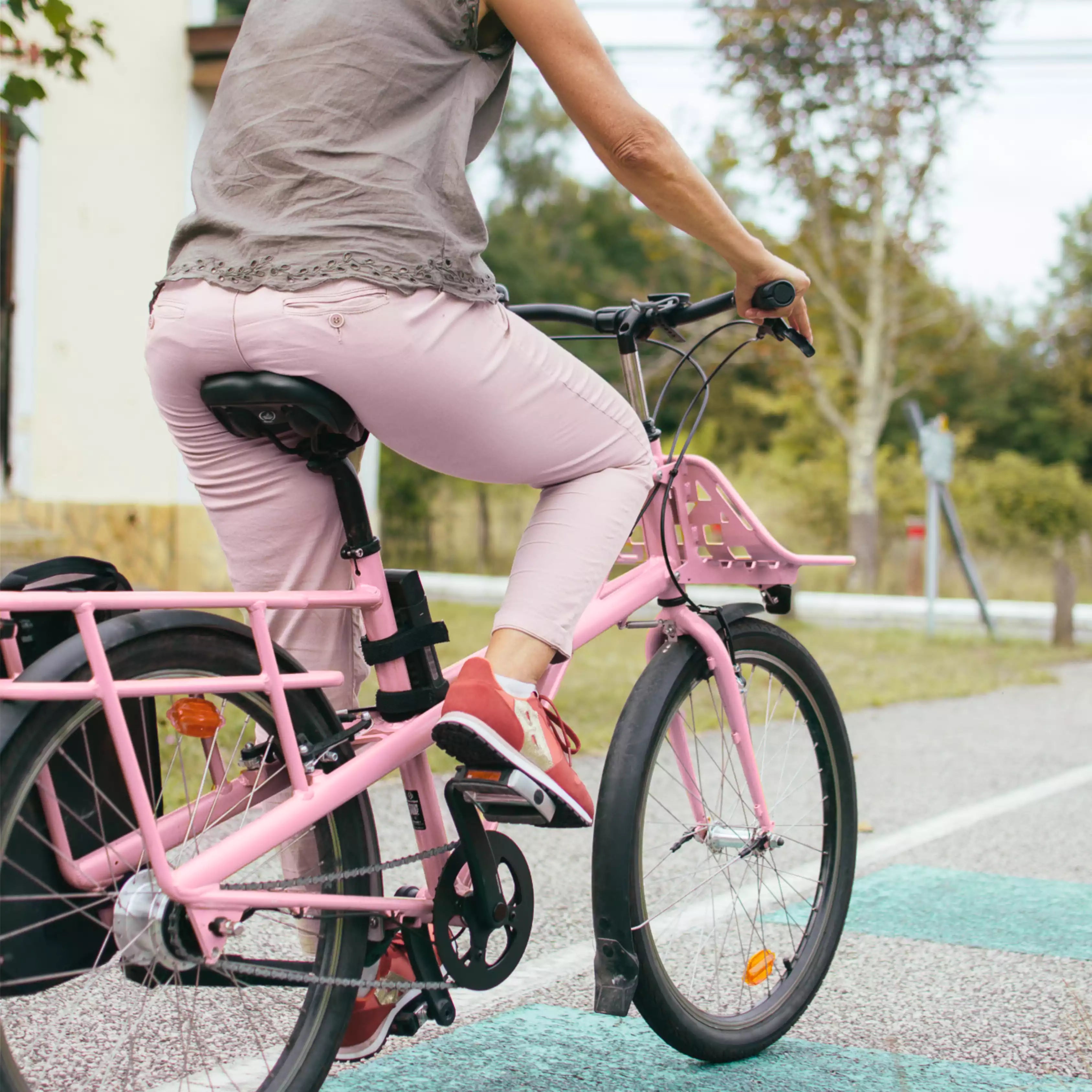 une femme avec un pantalon rose sur un vélo rose