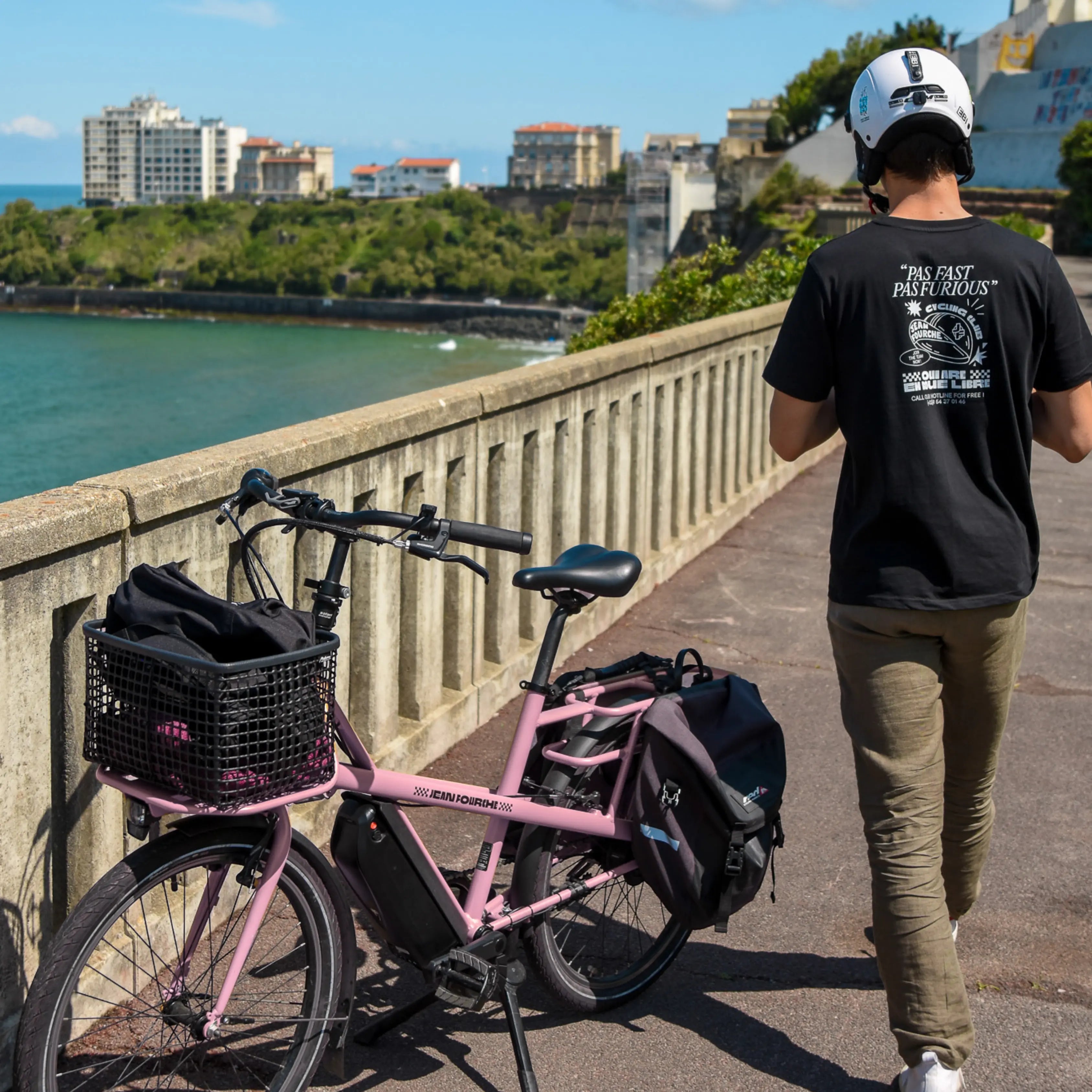 un homme de dos devant un vélo électrique rose