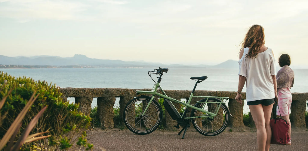 2 femmes de dos et un vélo vert devant la mer à Biarritz