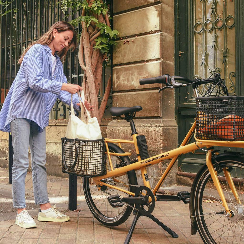 femme qui enleve son sac du porte bagage de son velo jaune